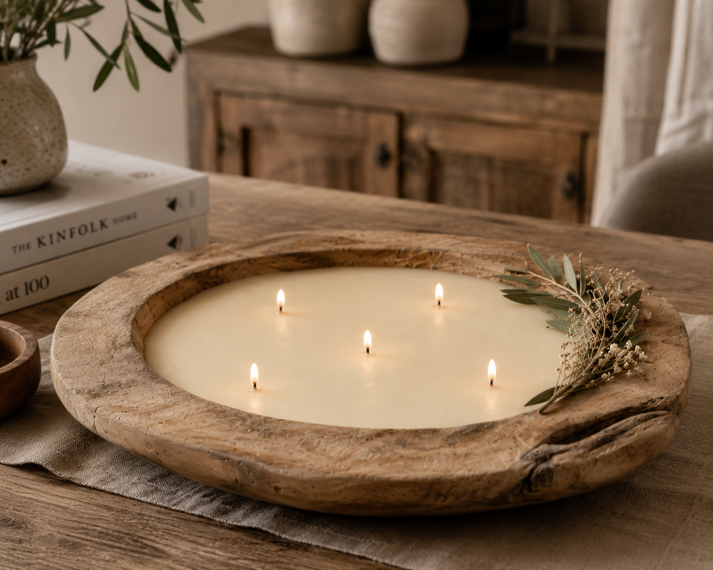 Vela artesanal encendida en bandeja de madera con ramas de olivo